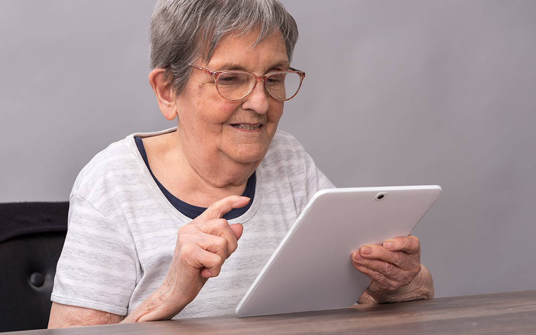 Eine ältere Dame hält ein Tablet in der rechten Hand